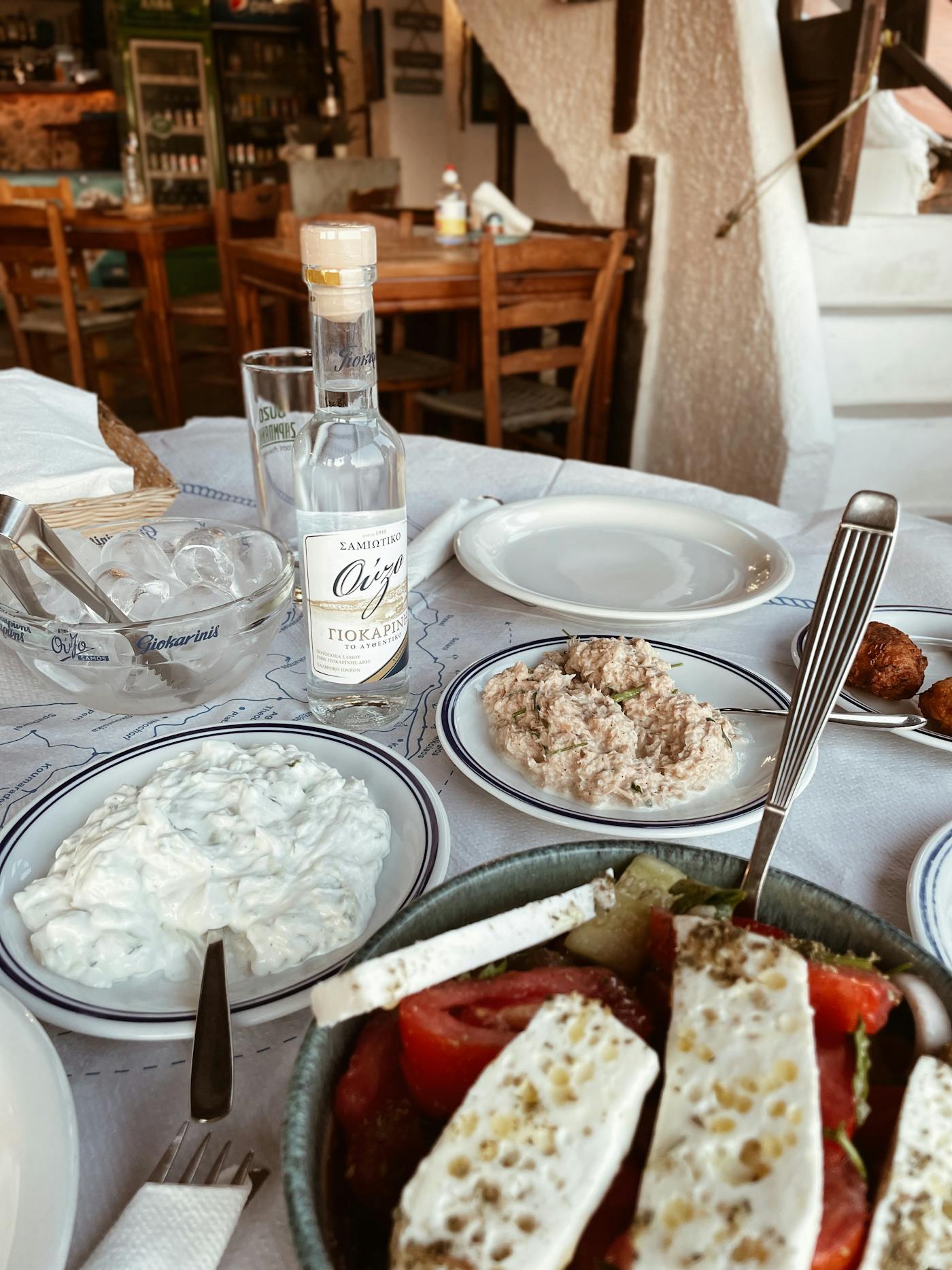 A small glass of zivania beside meze on a rustic table.